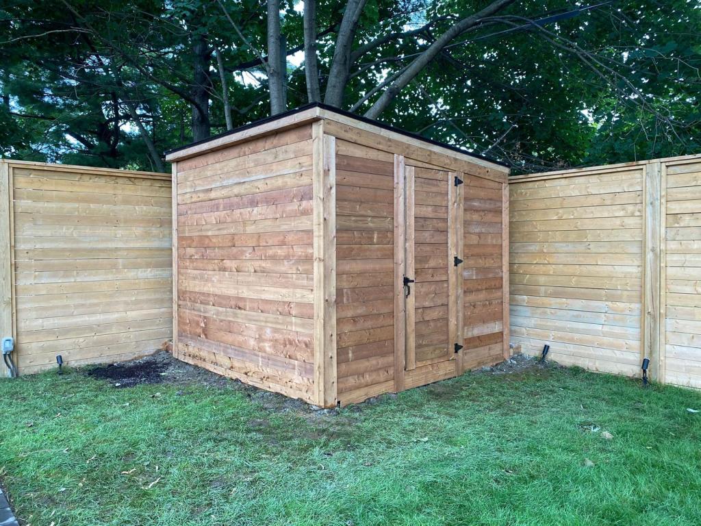 Wooden shed and fence with green lawn

