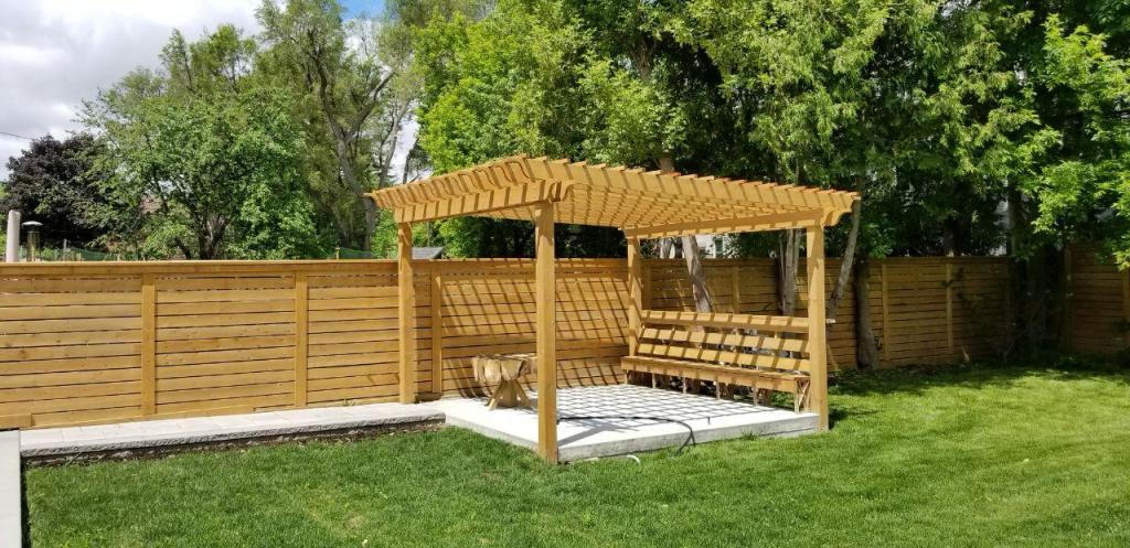 Wood gazebo with privacy fence and green lawn